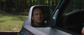 Movie still from “Insidious: The Red Door” (2023), directed by Patrick Wilson – A reflection of a man in the side view mirror of a car; Close Up shot, Over the shoulder angle