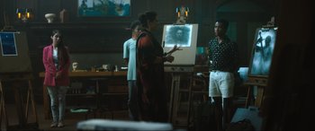 Movie still from “Insidious: The Red Door” (2023), directed by Patrick Wilson – A woman standing in front of an easel in a room; Wide shot, Over the shoulder angle