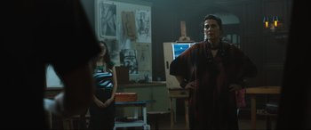 Movie still from “Insidious: The Red Door” (2023), directed by Patrick Wilson – A woman standing next to a girl in front of a painting; Medium shot, Low angle