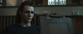 Movie still from “Insidious: The Red Door” (2023), directed by Patrick Wilson – A young man standing in a room next to an easel; Close Up shot, Low angle