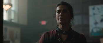 Movie still from “Insidious: The Red Door” (2023), directed by Patrick Wilson – An older woman wearing a necklace looking off into the distance; Close Up shot, Low angle