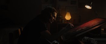 Movie still from “Insidious: The Red Door” (2023), directed by Patrick Wilson – A person sitting at a table in a dark room; Medium shot, Low angle