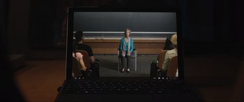 Movie still from “Insidious: The Red Door” (2023), directed by Patrick Wilson – A woman sitting on a chair in front of a group of people in front of a chalkboard; Wide shot, Over the shoulder angle