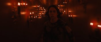 Movie still from “Insidious: The Red Door” (2023), directed by Patrick Wilson – A woman is standing in a dark room with candles in the background; Medium shot, Low angle