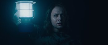 Movie still from “Insidious: The Red Door” (2023), directed by Patrick Wilson – A person holding a light in a dark room; Close Up shot, Low angle