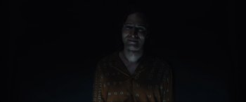 Movie still from “Insidious: The Red Door” (2023), directed by Patrick Wilson – A man in a brown shirt is in the dark; Medium shot, Low angle