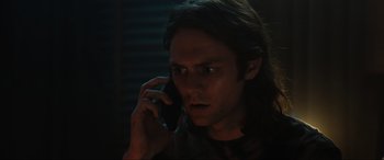Movie still from “Insidious: The Red Door” (2023), directed by Patrick Wilson – A man with long dark hair talking on a cell phone; Close Up shot, Low angle