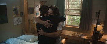 Movie still from “Insidious: The Red Door” (2023), directed by Patrick Wilson – Two people hugging in a room with a window in the background; Medium shot, High angle