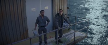 Movie still from “Interceptor” (2022), directed by Matthew Reilly – Two men standing on the deck of a boat; Wide shot, High angle