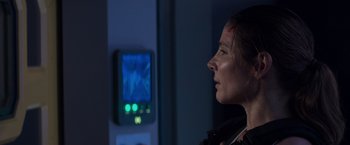 Movie still from “Interceptor” (2022), directed by Matthew Reilly – A woman looking into the distance in front of a television; Close Up shot, Over the shoulder angle