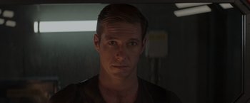 Movie still from “Interceptor” (2022), directed by Matthew Reilly – A person wearing a black t - shirt; Close Up shot, Over the shoulder angle