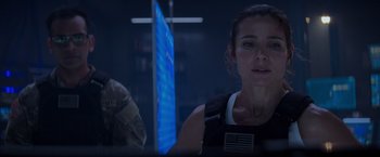 Movie still from “Interceptor” (2022), directed by Matthew Reilly – A person with a flag in the background; Close Up shot, Over the shoulder angle