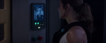 Movie still from “Interceptor” (2022), directed by Matthew Reilly – A woman standing in front of a wall with a picture on it; Close Up shot, Over the shoulder angle