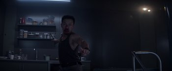 Movie still from “Interceptor” (2022), directed by Matthew Reilly – A man in a dark room holding a knife; Medium shot, Low angle