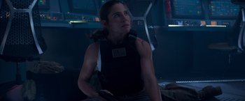 Movie still from “Interceptor” (2022), directed by Matthew Reilly – A woman in a black vest is holding a gun; Medium shot, Low angle