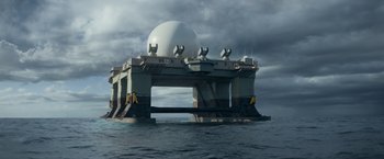 Movie still from “Interceptor” (2022), directed by Matthew Reilly – A large structure in the middle of the ocean under a cloudy sky; Extreme Wide shot, Low angle