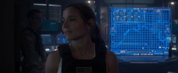 Movie still from “Interceptor” (2022), directed by Matthew Reilly – A woman in a black tank top is standing in front of a wall; Close Up shot, Over the shoulder angle