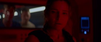 Movie still from “Interceptor” (2022), directed by Matthew Reilly – A woman in a dark room with red lighting; Close Up shot, Over the shoulder angle