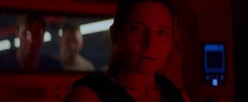 Movie still from “Interceptor” (2022), directed by Matthew Reilly – A woman in a dark room with red lighting; Close Up shot, Over the shoulder angle