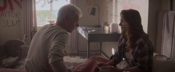 Movie still from “Interceptor” (2022), directed by Matthew Reilly – An older man and a young woman sitting on a bed; Medium shot, Over the shoulder angle