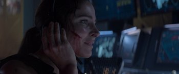Movie still from “Interceptor” (2022), directed by Matthew Reilly – A woman in a dark room wearing a headset; Close Up shot, Over the shoulder angle