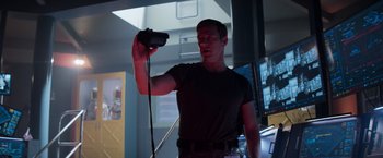 Movie still from “Interceptor” (2022), directed by Matthew Reilly – A man holding a video game controller in a dark room; Medium shot, Low angle