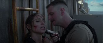 Movie still from “Interceptor” (2022), directed by Matthew Reilly – A man holding a cell phone next to a woman with blood all over her face; Close Up shot, Over the shoulder angle
