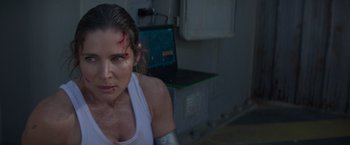 Movie still from “Interceptor” (2022), directed by Matthew Reilly – A woman in a white shirt with a laptop in front of her face; Close Up shot, Over the shoulder angle
