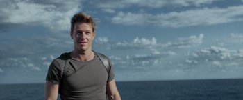 Movie still from “Interceptor” (2022), directed by Matthew Reilly – A man standing in front of a body of water; Medium shot, Low angle