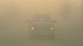 A truck is driving through the fog on the road