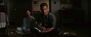 Movie still from “Interstellar” (2014), directed by Christopher Nolan – A man sitting on the ground writing in a notebook; Medium shot, Over the shoulder angle