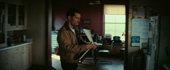 A man in a brown jacket is holding a white stick