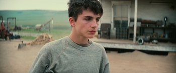 Movie still from “Interstellar” (2014), directed by Christopher Nolan – A young man in a gray shirt is looking at the camera; Close Up shot, Over the shoulder angle
