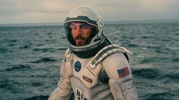 Movie still from “Interstellar” (2014), directed by Christopher Nolan – A man in a spacesuit standing in the water; Medium shot, Over the shoulder angle