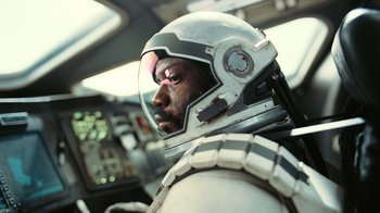 Movie still from “Interstellar” (2014), directed by Christopher Nolan – A man in a space suit and helmet in a cockpit of an airplane; Close Up shot, Overhead angle