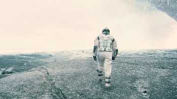 Movie still from “Interstellar” (2014), directed by Christopher Nolan – A person in a spacesuit is walking on the ground; Wide shot, Low angle