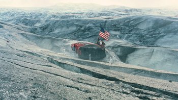 Movie still from “Interstellar” (2014), directed by Christopher Nolan – An american flag flies on top of an overturned truck; Extreme Wide shot, High angle