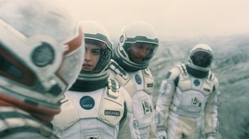 Movie still from “Interstellar” (2014), directed by Christopher Nolan – A group of people in spacesuits standing next to each other; Medium shot, Over the shoulder angle