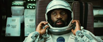 Movie still from “Interstellar” (2014), directed by Christopher Nolan – A man in a spacesuit is putting on a helmet; Close Up shot, Overhead angle