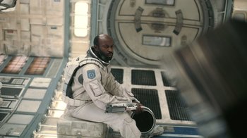 Movie still from “Interstellar” (2014), directed by Christopher Nolan – A man sitting on top of a wall in a space suit; Medium shot, High angle