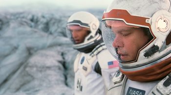 Movie still from “Interstellar” (2014), directed by Christopher Nolan – Two men in spacesuits standing next to each other; Close Up shot, Overhead angle