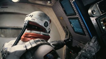 Movie still from “Interstellar” (2014), directed by Christopher Nolan – A person in a space suit is looking at a computer screen; Medium shot, Overhead angle