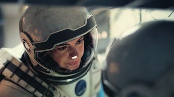 Movie still from “Interstellar” (2014), directed by Christopher Nolan – A woman wearing a space suit and a helmet; Close Up shot, Low angle