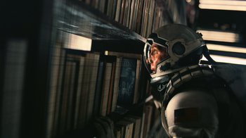 Movie still from “Interstellar” (2014), directed by Christopher Nolan – A man in a spacesuit looking out a window; Close Up shot, Overhead angle