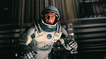 Movie still from “Interstellar” (2014), directed by Christopher Nolan – A man in a spacesuit is holding something in his hand; Medium shot, Overhead angle