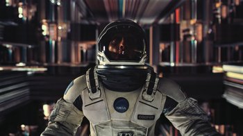 Movie still from “Interstellar” (2014), directed by Christopher Nolan – A man in a spacesuit is standing in a room; Medium shot, Overhead angle