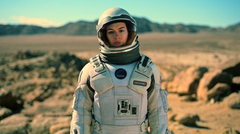 Movie still from “Interstellar” (2014), directed by Christopher Nolan – A woman in a spacesuit standing in the desert; Medium shot, Low angle
