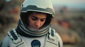 Movie still from “Interstellar” (2014), directed by Christopher Nolan – A woman in a space suit is looking down; Close Up shot, Overhead angle