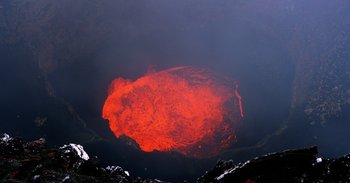 Movie still from “Into the Inferno” (2016), directed by Werner Herzog – A crater of a volcano with a red glow in it; Extreme Wide shot, High angle