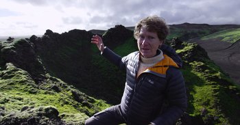 Movie still from “Into the Inferno” (2016), directed by Werner Herzog – A woman standing on top of a mountain; Medium shot, High angle